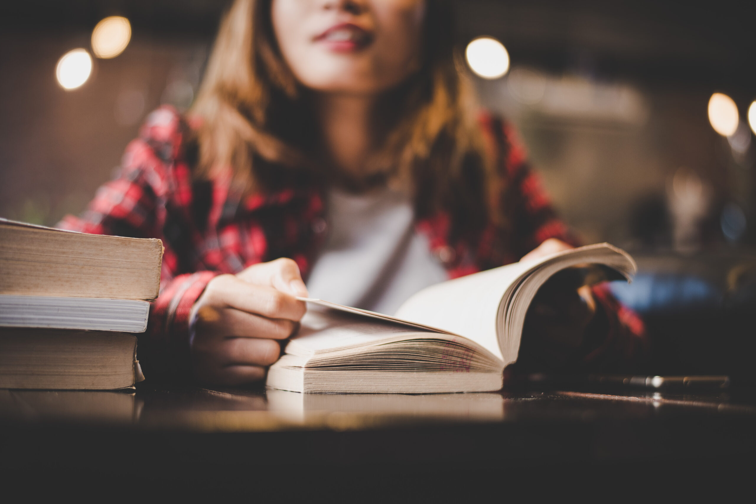Close up of woman sitting and reading a book at a table
