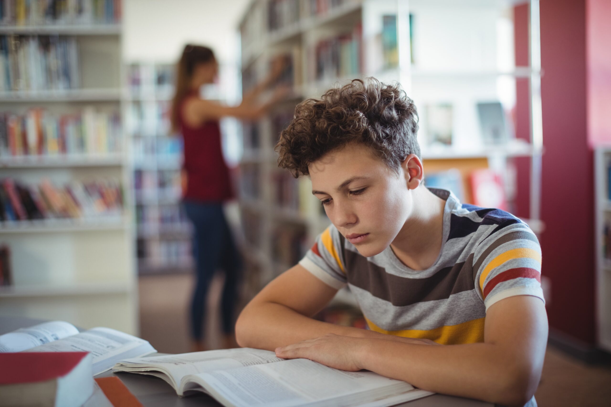 Schoolboy reading book in library