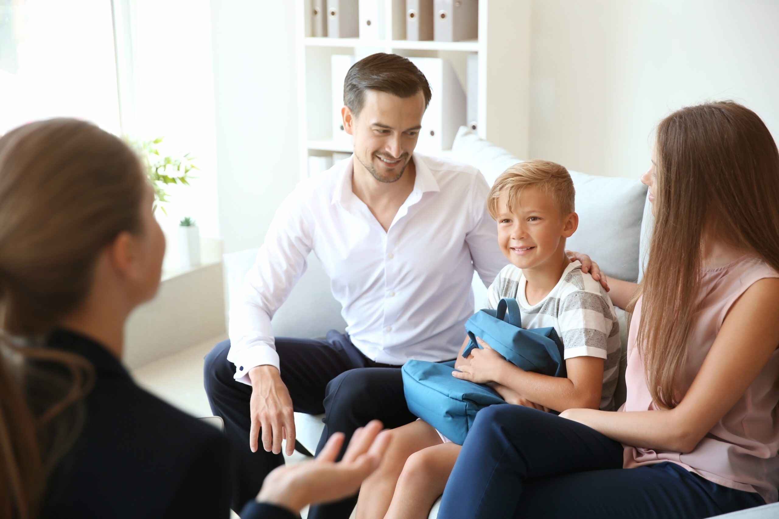 Young couple and their son meeting with teacher at school