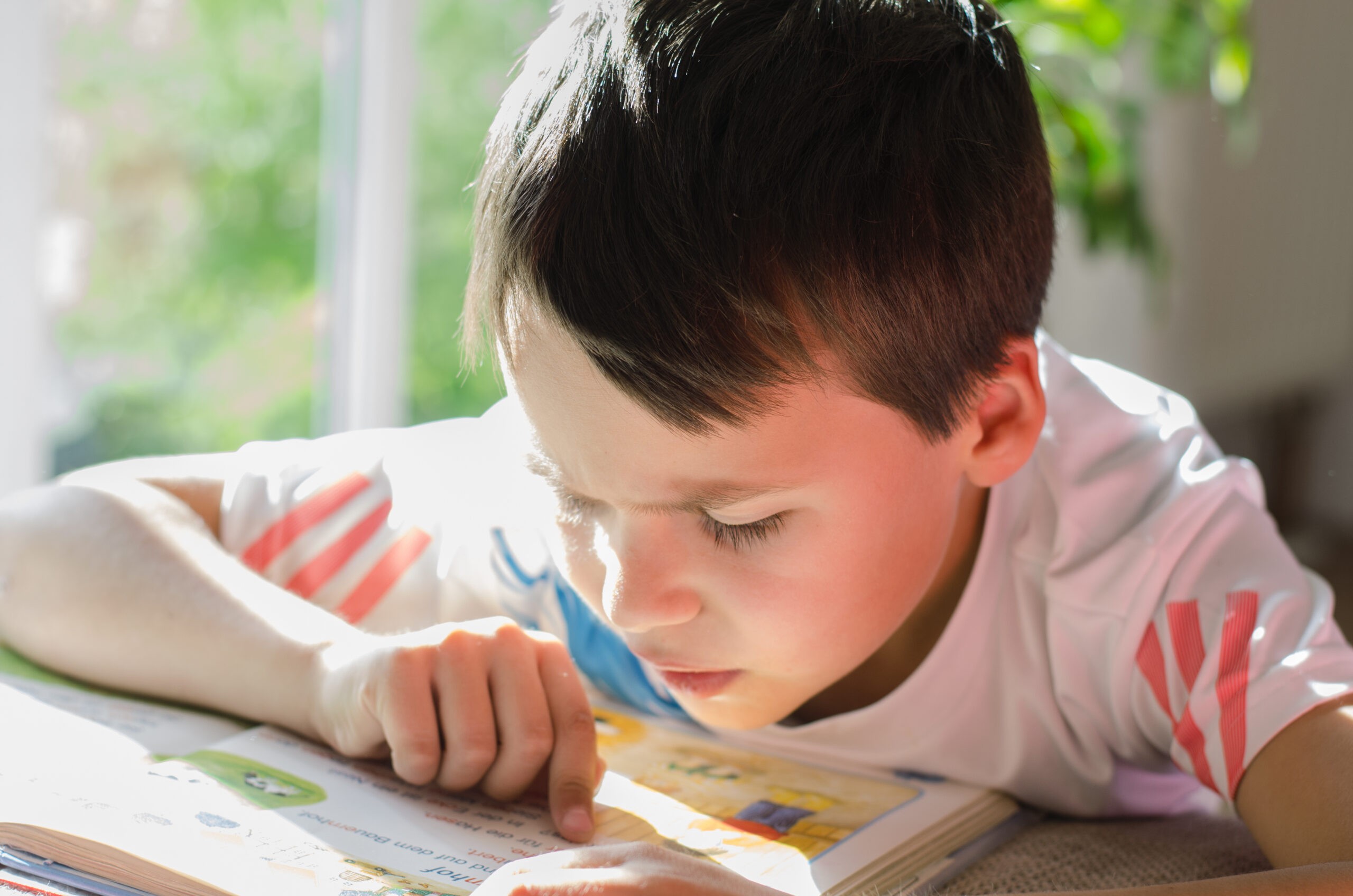 Close up of young boy reading and following along with his finger